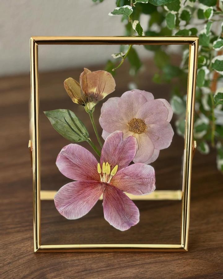 Pressed delicate flowers framed in gold glass frame by @sampaguitapressca showcasing nature-inspired paper craft art.
