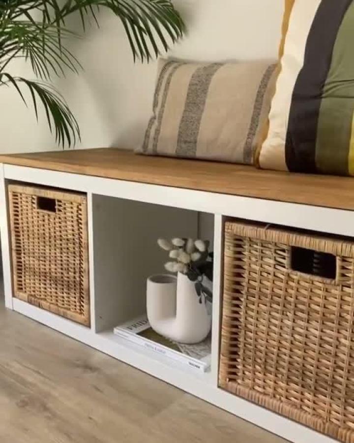 Natural wicker baskets on white wooden bench with cushions from @tidyorganization.co. Cozy, stylish storage seating idea.