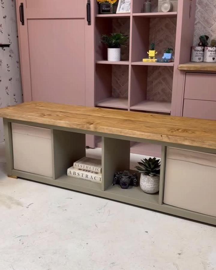 Light sage-green Kallax-style bench with natural wood top and neutral fabric bins by @do.it.yourself.mum. Cozy storage and display seating piece.
