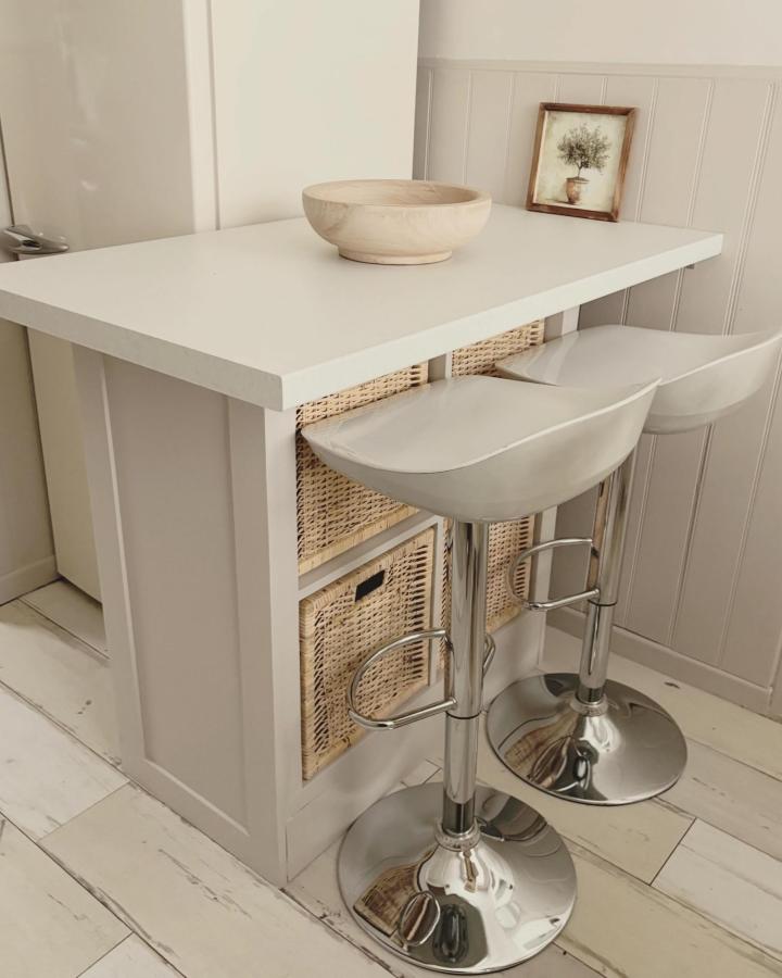 White and natural woven basket kitchen island from @ourlittleneutralnest featuring ikea kallax hacks with sleek white countertop and modern stools.