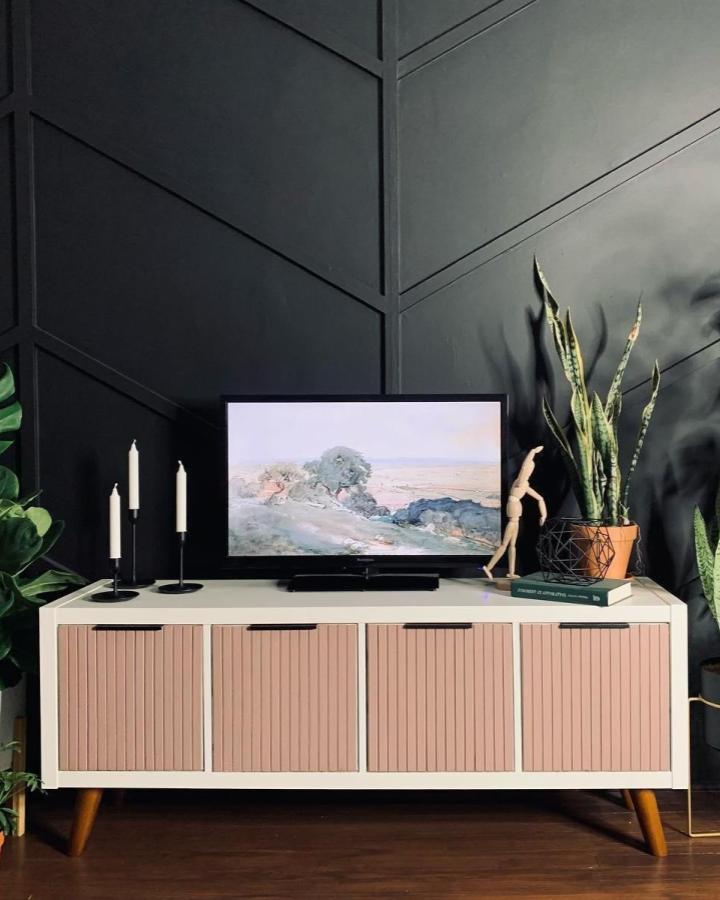 Blush slatted door media console with wooden legs in cozy living room from @familyrenov8. Stylish storage upgrade with sleek modern feel.