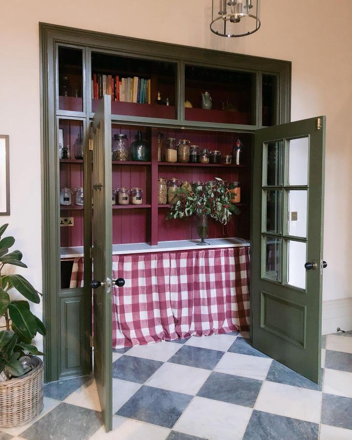 Olive green and plum painted pantry nook with checkered curtain from @fallowgrey showcasing creative storage and vintage charm.