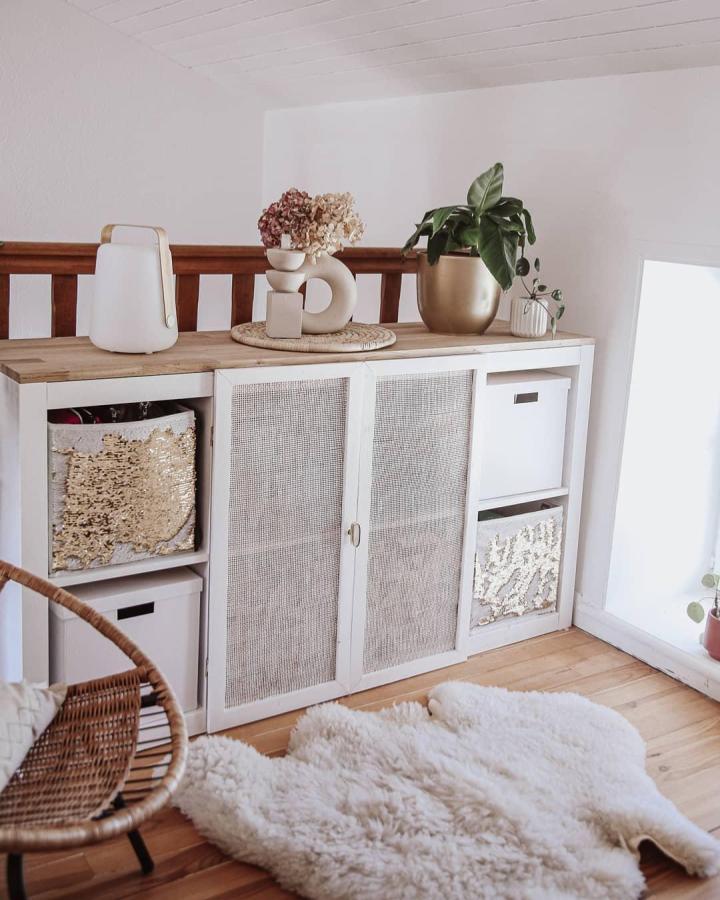 White and natural wood storage unit with woven textured doors and gold accents by @casa.la.foret. Cozy and stylish room storage upgrade.