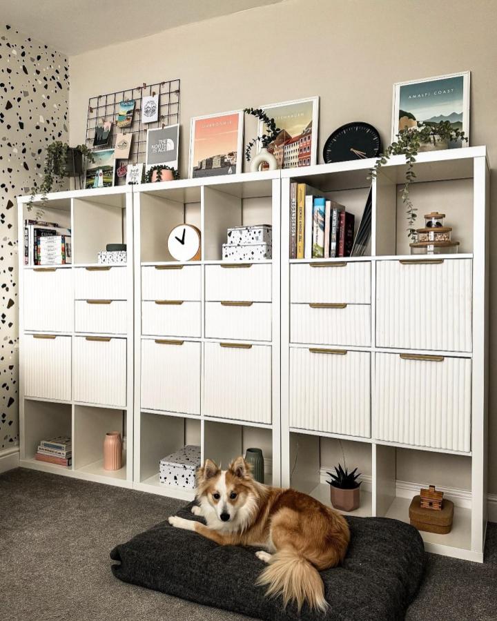 White ribbed front storage unit with brass handles in living room from @kate.at.number8. Modern textured drawer makeover on modular shelving.