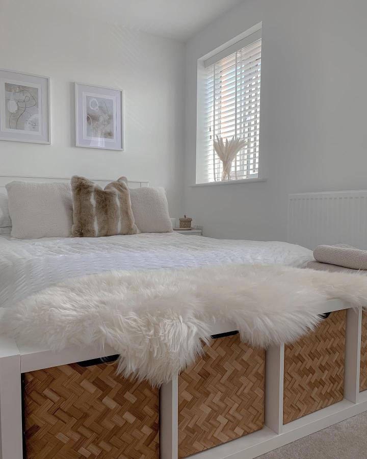 White faux fur topped bench with natural woven storage baskets below from @counterproductivehome in a minimalist bedroom setting. Cozy and practical storage seating.