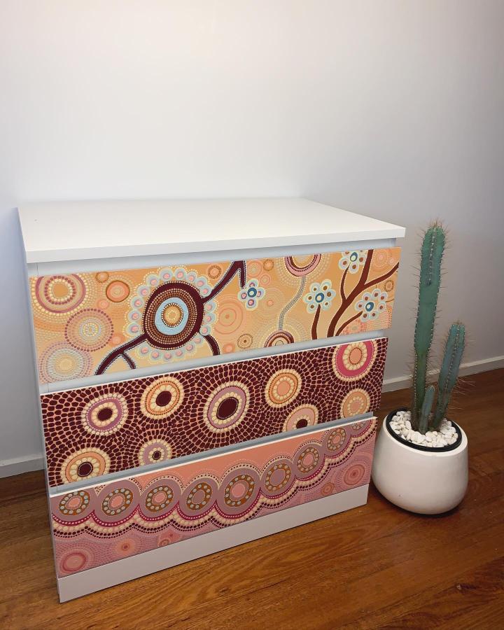 Ochre and rust Aboriginal style drawer fronts on white dresser from @kamilyalowana featuring circular dot painting design. Vibrant cultural update.