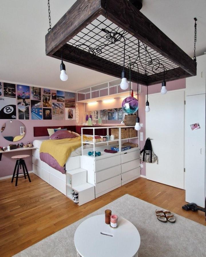White modern bedroom platform bed with built-in drawers and step storage from @outhausberlin. Multifunctional elevated sleeping area.
