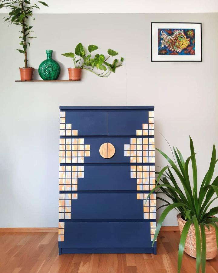 Navy blue dresser with natural wood tile accents and round handle in a living space from @nadruhypohled modern geometric storage piece.