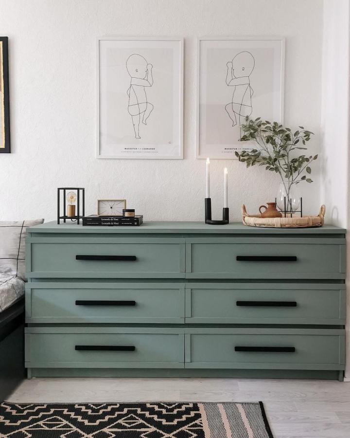 Sage green Ikea Malm dresser hack from @leoxbella with black handles and minimalist decor in cozy living space.