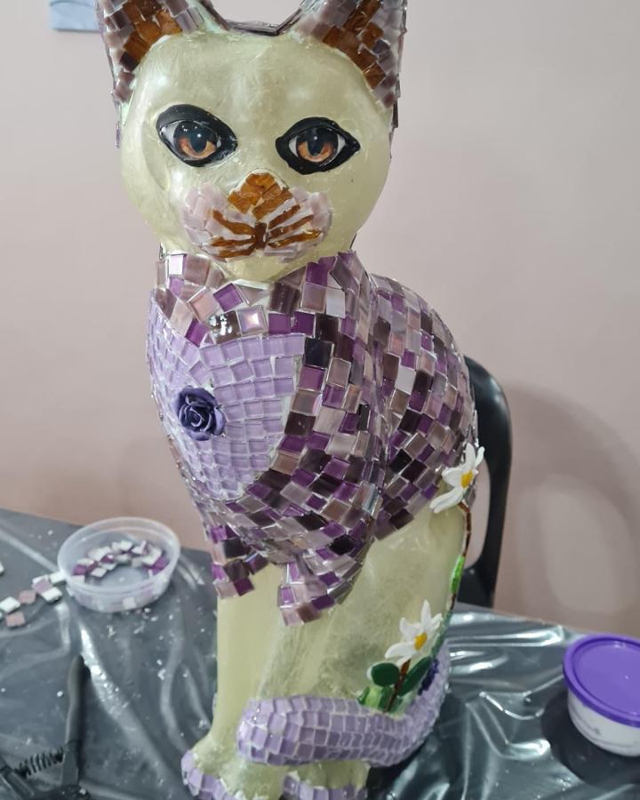 Purple and lilac tiled cat sculpture with floral accents from @serenitiesartstudio showing creative mosaic tile crafting. Detailed and textured.