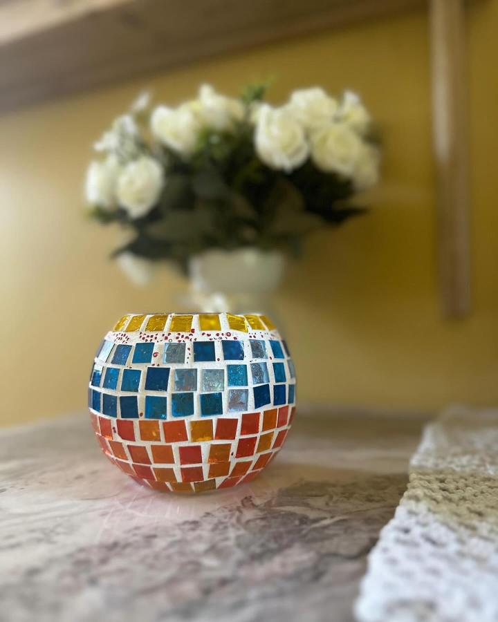 Orange blue yellow glass tile mosaic candle holder from @mirrorsmosaicmagic. Colorful handmade decor with glowing light effect.