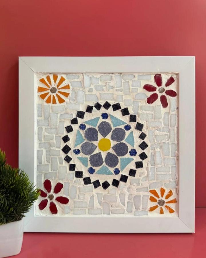 Colorful floral mosaic tile artwork from @poojas_art_classes. Framed tile craft featuring bright petals and geometric center on white background.