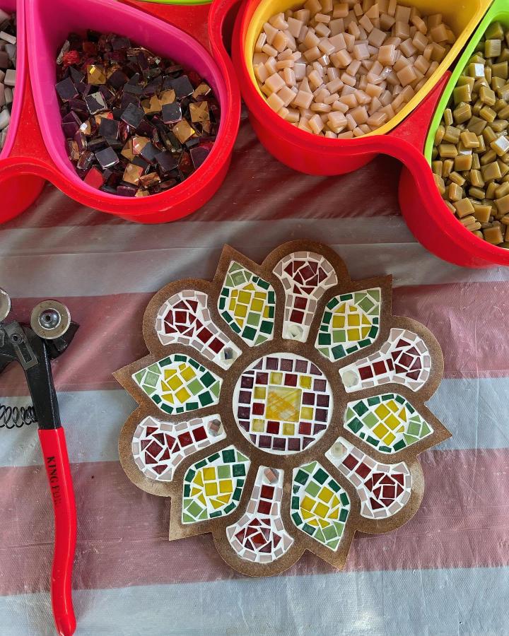 Red yellow and green floral mosaic tile craft idea on wooden base with tile cutters from @farina.aesthetic. Bright and earthy tones in mosaic tile craft ideas.