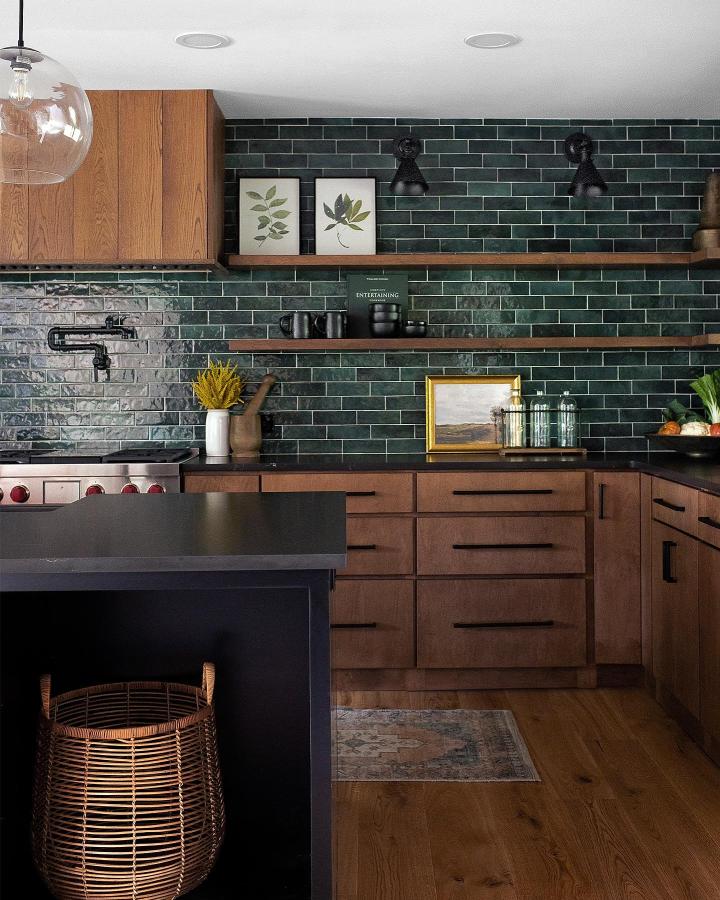 Dark green tiled backsplash kitchen with wooden floating shelves and black accents from @houseliftdesign showing open shelving ideas for your kitchen with natural and modern balance.
