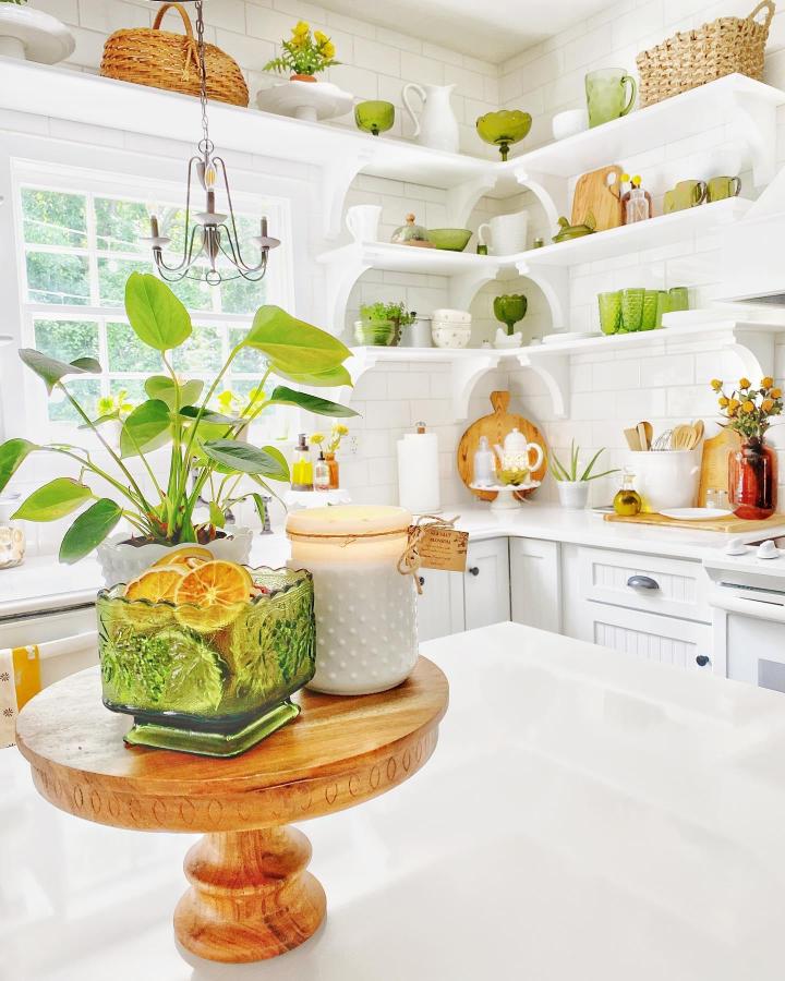 Green vintage glass and white wooden shelves kitchen nook from @kozycolonialhome with cozy rustic charm and natural light.