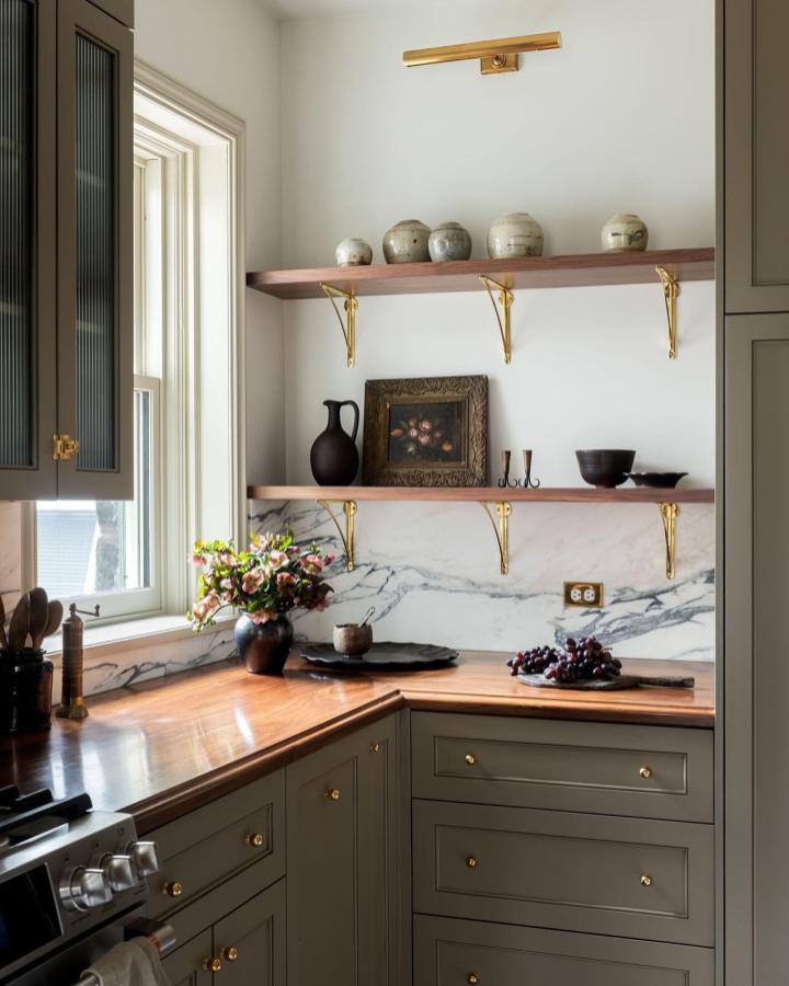 Warm brass bracket and natural wood floating shelves in kitchen corner from @mcbecks_pix. Stylish storage meets elegant rustic charm.