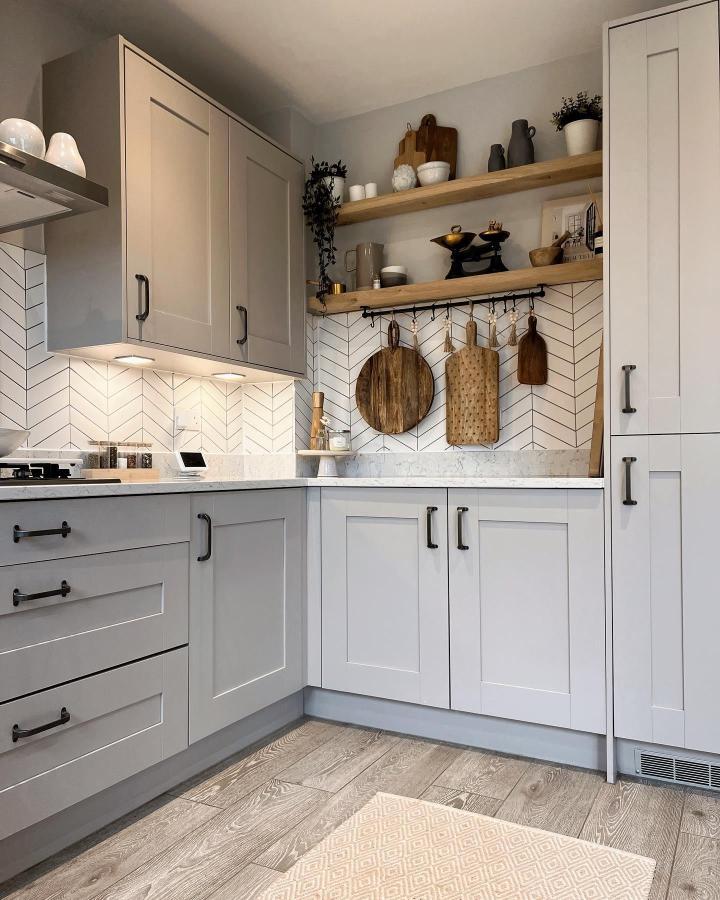 Light wood floating shelves and gray cabinets in a kitchen corner from @scarlett_at_home. Rustic cutting boards and neat storage.