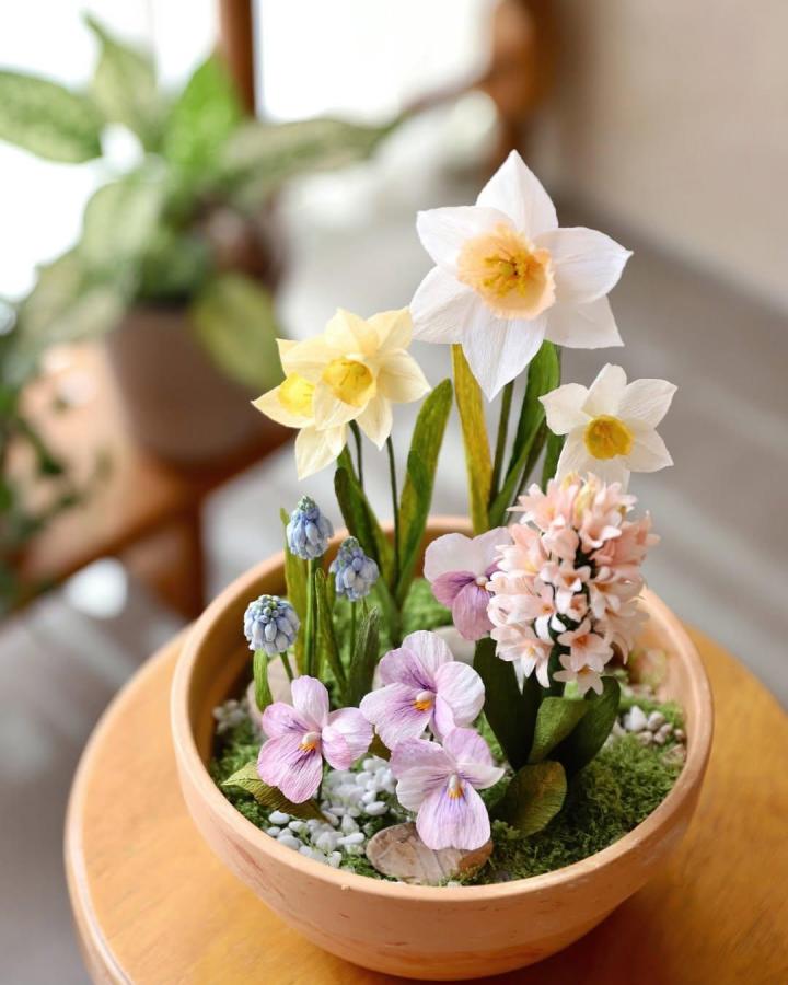 Soft pastel crepe paper mini garden with daffodils and hyacinths from @marie.blooming showing delicate paper flower crafts for adults in a shallow terracotta pot.