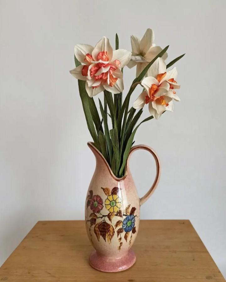 Cream and coral crepe paper flowers in vintage floral pitcher from @_florissante_ showcasing delicate handcrafted blooms with green leaves and soft texture.