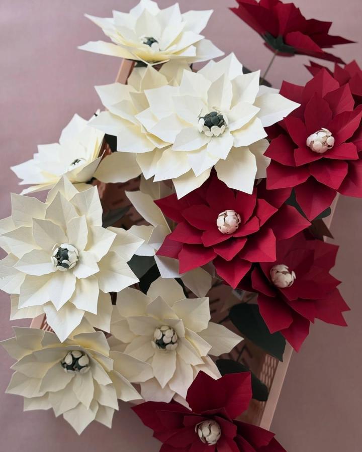 Creamy and bold red dyed crepe paper flowers with green accents by @farrenceleste showing layered floral craft details.