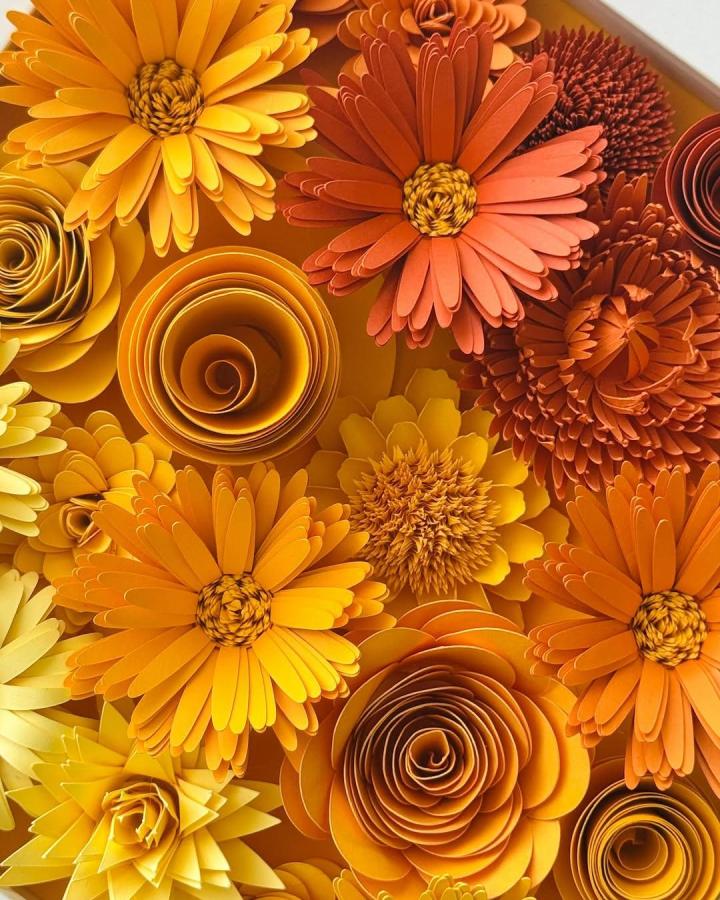 Bright orange and yellow framed paper flower arrangement by @floralflairstudio featuring layered petals and spiral centers in warm hues.