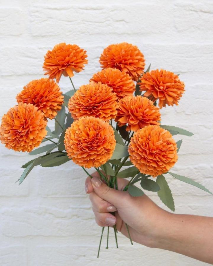 Orange layered marigold paper flowers with green leaves from @farrenceleste showcasing vibrant paper flower crafts for adults. Bright and detailed bouquet.