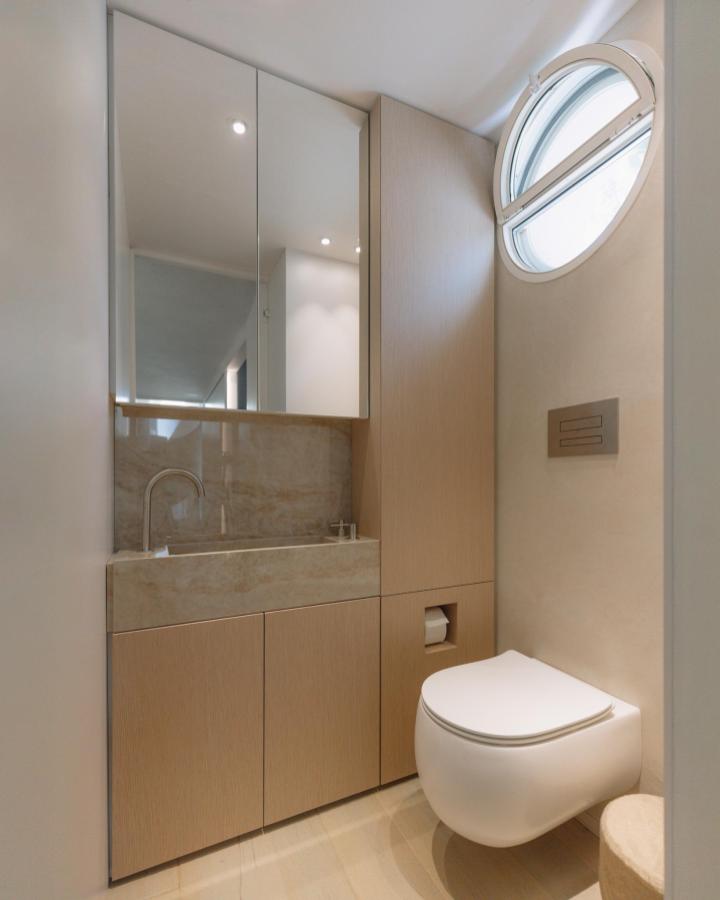 Light wood cabinetry and beige stone sink in a compact bathroom by @piertitocardillostudio with smart integrated storage. Bright and clean design.
