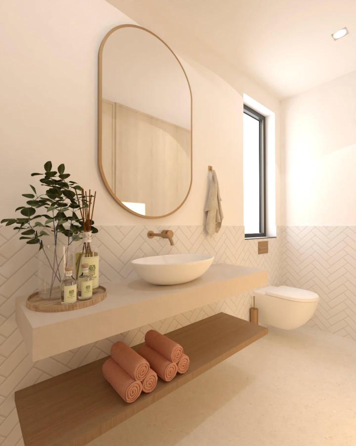 Beige and warm wood floating shelves in a powder room by @lilliehelena_designhouse with rolled towels and subtle herringbone tiles.