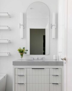 Rippled white cabinet fronts with sleek gray countertop by @jeffreydouglasdesign for stylish compact bathroom storage. Modern minimalist vibe.