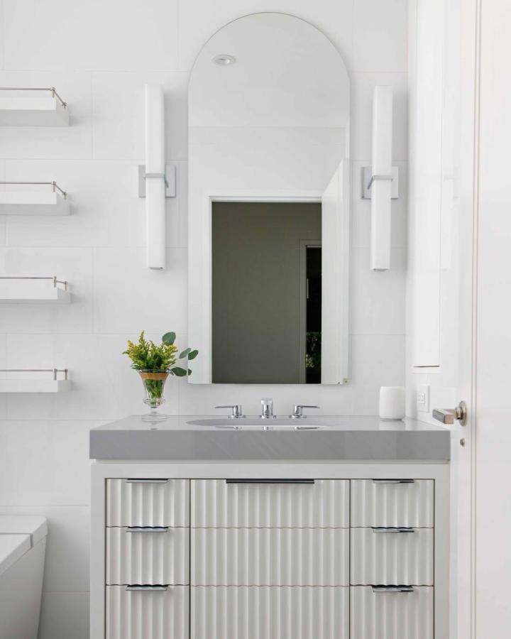 Rippled white cabinet fronts with sleek gray countertop by @jeffreydouglasdesign for stylish compact bathroom storage. Modern minimalist vibe.