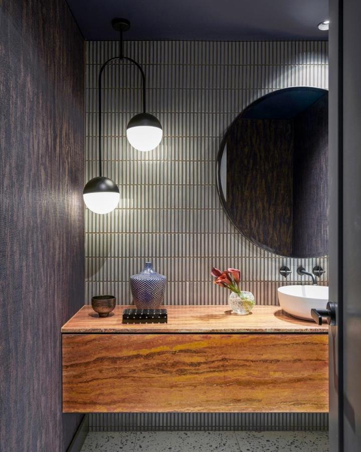 Light wood floating vanity in a modern bathroom by @kaiko_design with hidden storage and decorative tile wall backdrop.