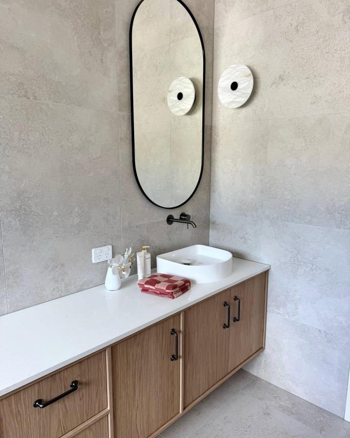 Natural wood floating vanity with black handles by @elizagraceinteriors Clean modern powder room storage with drawers and doors.