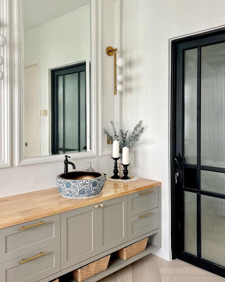 Gray floating vanity with natural woven baskets by @mysame_home stylishly organizing bathroom essentials below countertop.