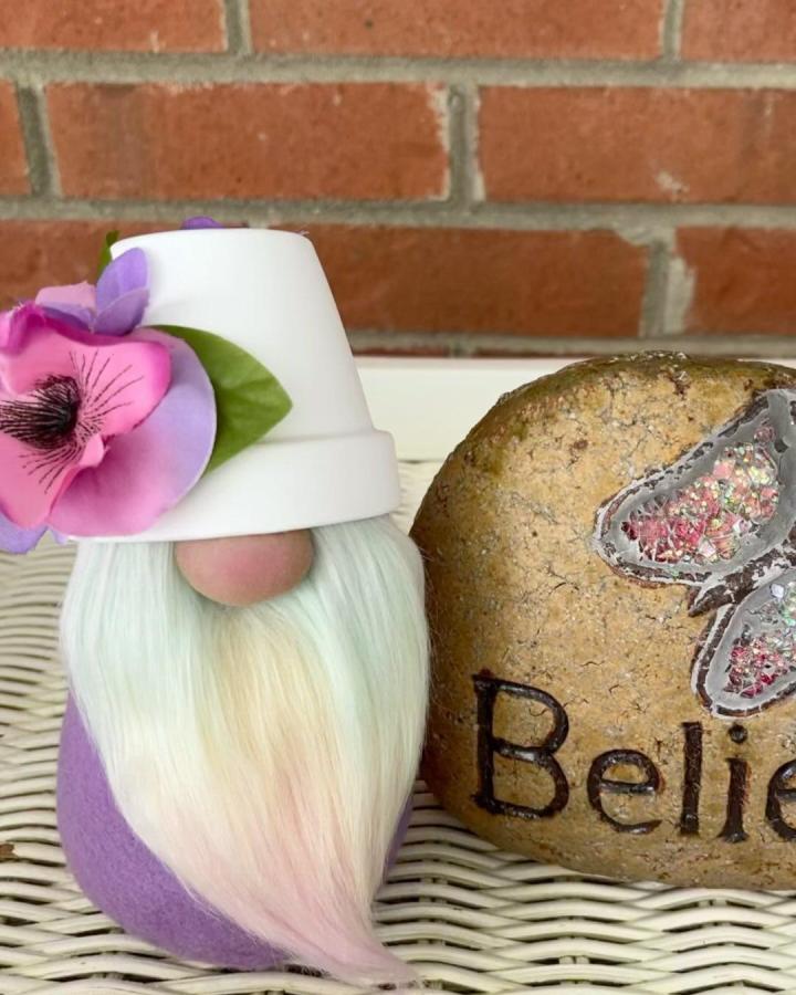 Terracotta pot crafts featuring a white pot hat gnome with pastel beard and floral detail from @marigold_perspective1. Whimsical and colorful DIY craft project.