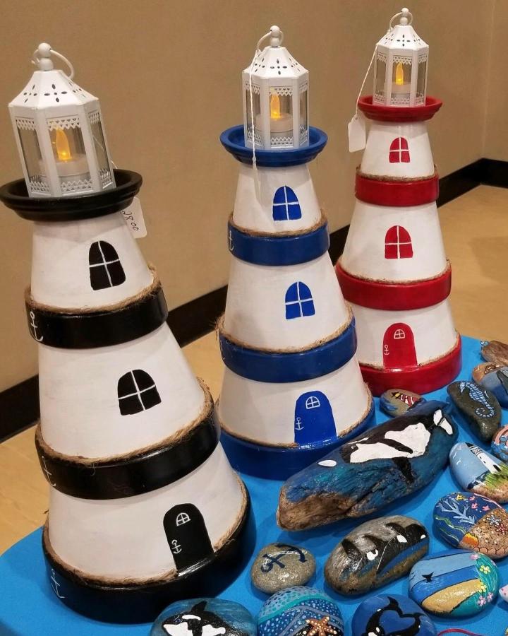 Red Blue And Black Painted Stacked Clay Pot Lighthouse Lanterns By @tootsiebellacrafts Displayed With Painted Rocks On Blue Tablecloth