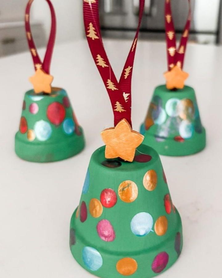 Bright green terracotta pot crafts with colorful painted dots and wooden star tops by @mariebostwick. Festive Christmas bell ornaments.