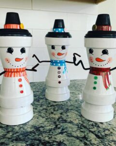Glossy white snowmen made from stacked clay pots with colorful scarves and hats by @g_screation_s. Festive DIY decor.