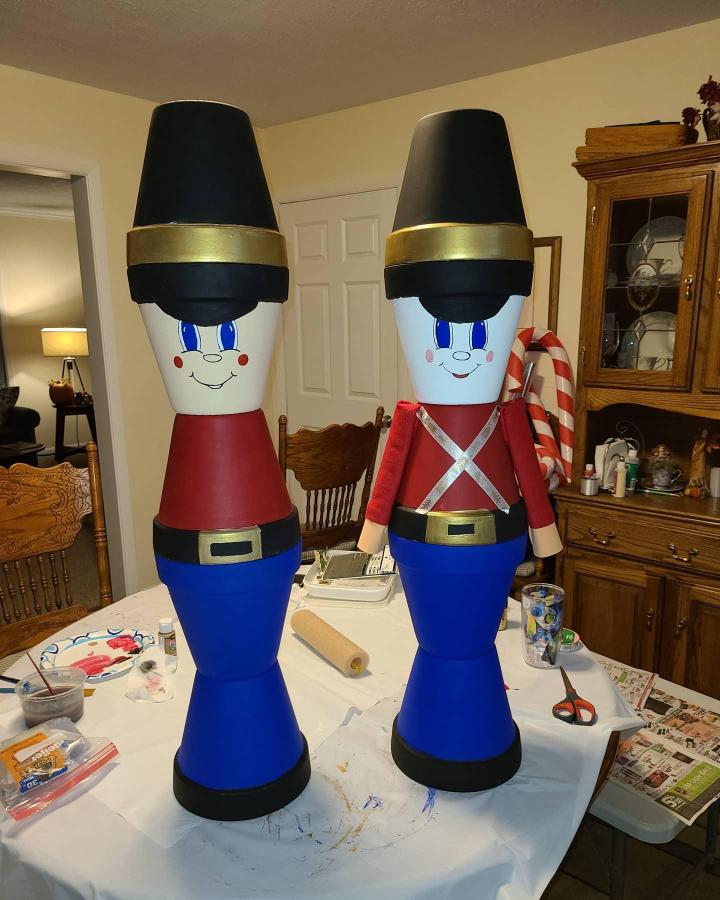 Bright colorful terracotta pot crafts of soldier figures from @jleighkn with hand-painted faces and gold accents on black hats.