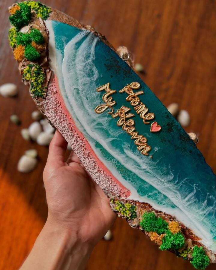 Teal resin ocean-wave sign from @zoohi.arts. Beach crafts for adults with gold lettering, coral edging, and mossy details.