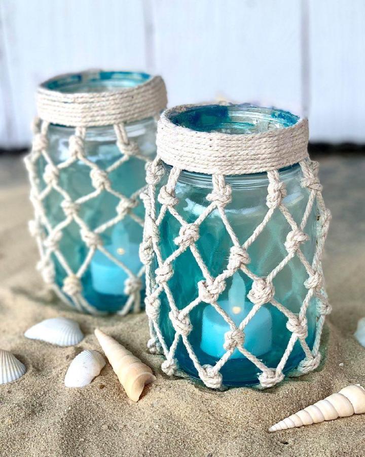 Turquoise rope-net jar lanterns from @dollargeneral. Beach-inspired glass decor with shells and sandy texture.