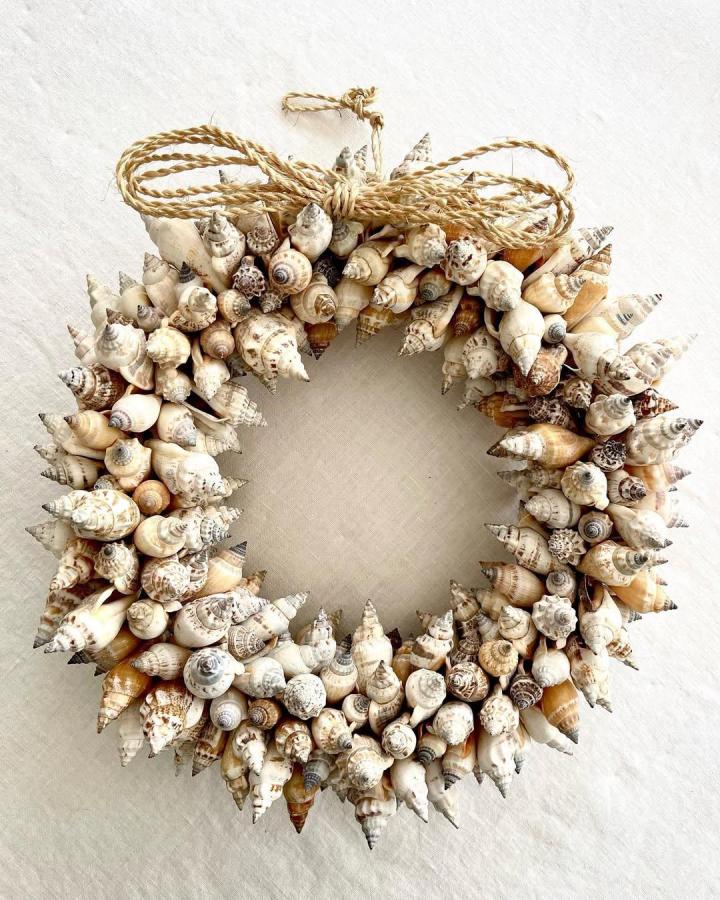 Ivory shell nautical wreath from @shop.sycamorecottage. Natural seashells and tan rope create a textured coastal accent.