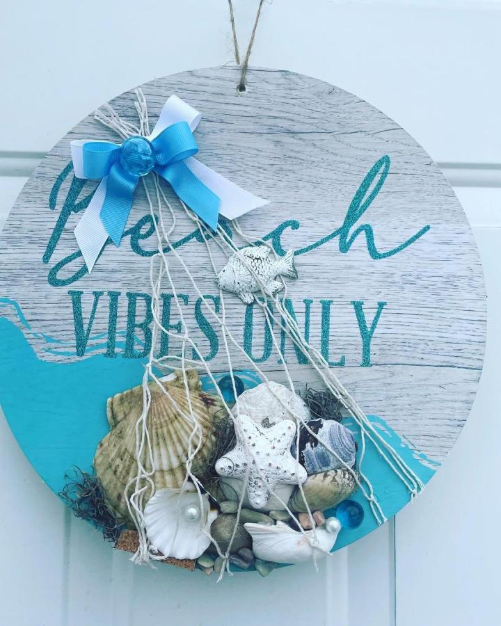 Turquoise and white shell beach crafts for adults sign from @by_natalidiy. Round coastal plaque with rope, shells, and bow.