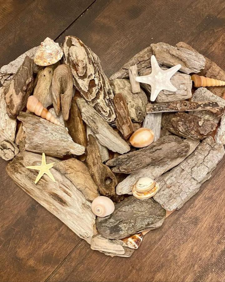 Natural driftwood shell heart craft from @seadriftdecor. Ivory starfish and shells accent the rustic design.