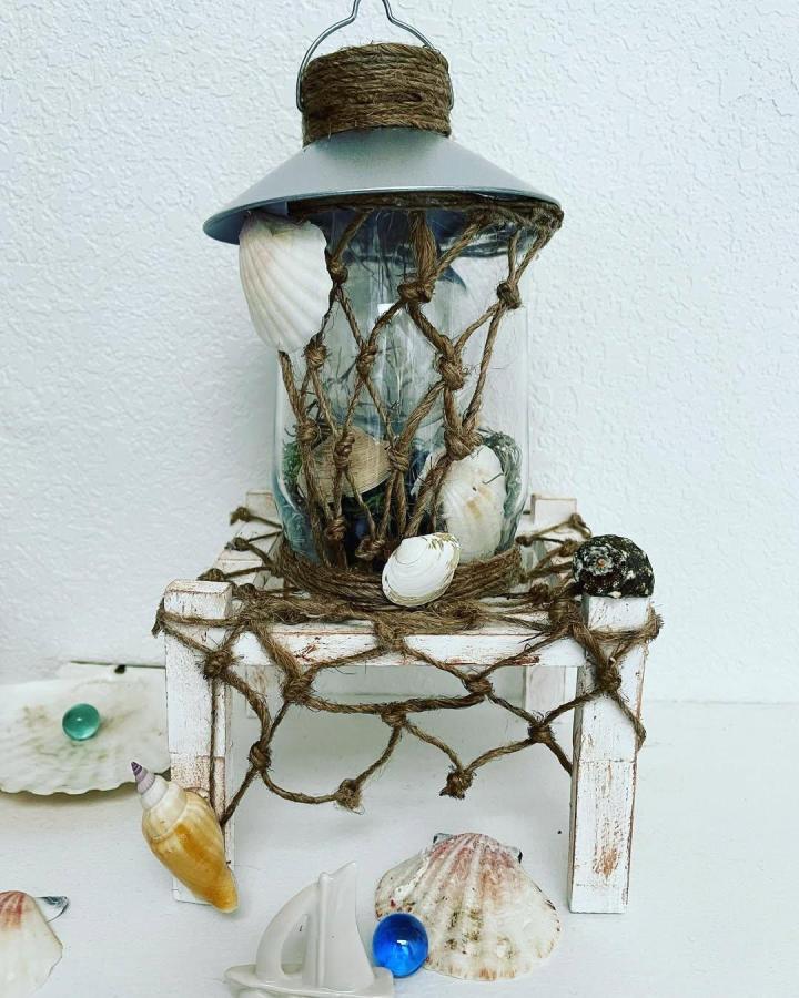 Brown jute shell lantern from @by_natalidiy. Rustic coastal craft with shells and knotted twine.