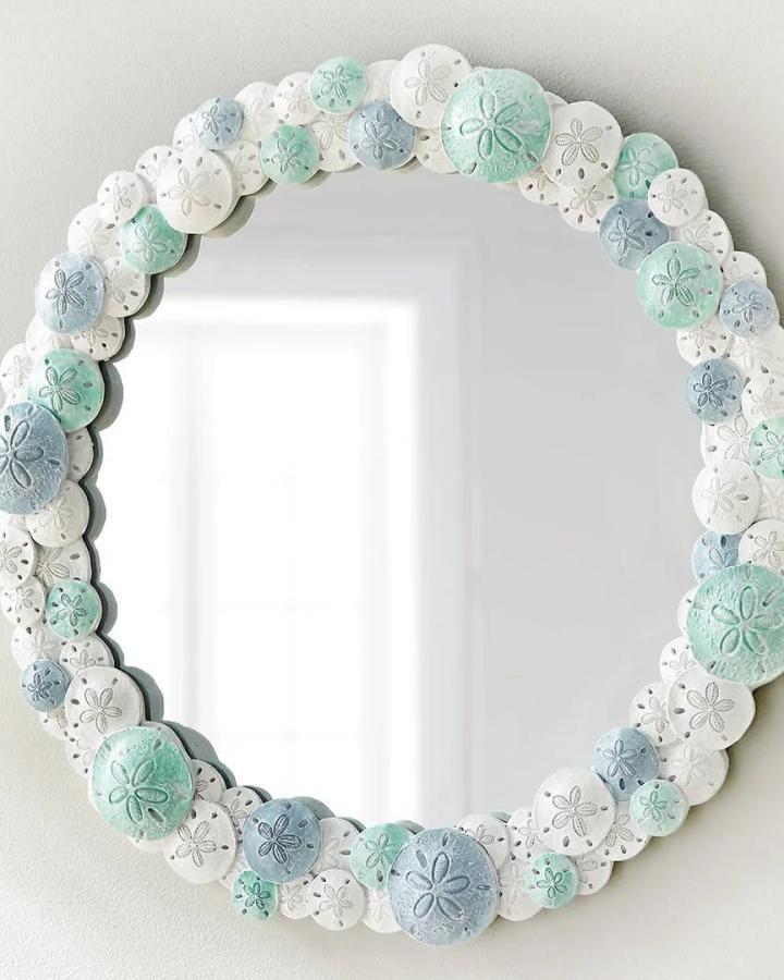Seafoam and white sand dollar mirror from @bellacoastaldecor. Layered shell detailing suits coastal crafting.