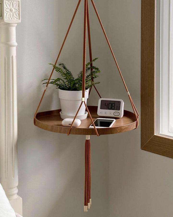 Warm brown suspended plant tray from @letme_bemyself. Leather cords hold a white pot beside a sunny window.