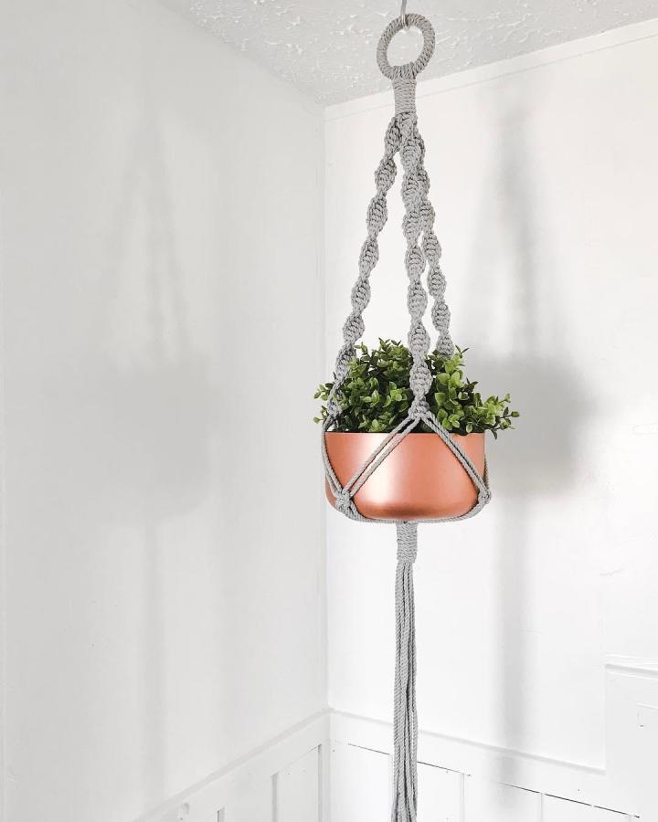 Gray braided diy macrame plant hanger from @holmmademacrame. Copper pot with leafy green plant.