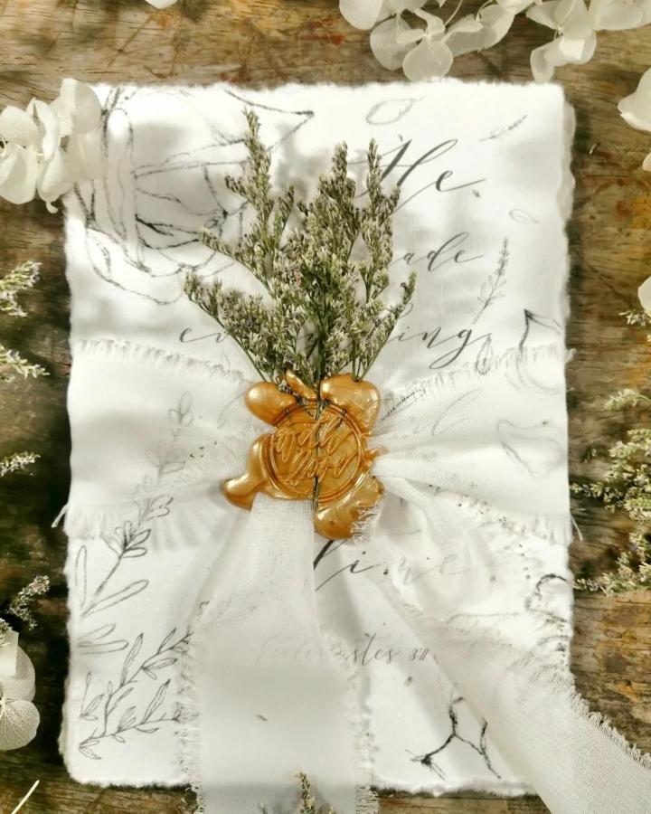 Ivory scripted napkin craft from @invitationsbyten. Gold wax seal and greenery highlight diy wedding crafts.