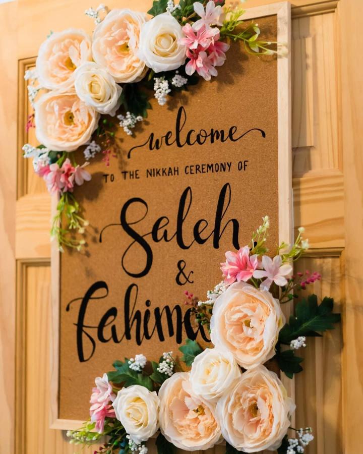 Peach and ivory floral welcome sign from @tehmeenaphotography. Handmade nikah ceremony display with pink blooms.