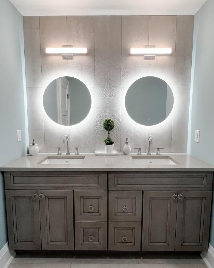 Gray textured double vanity bathroom from @mchomeimprovements. Round mirrors, white countertop, and glowing sconces create a balanced wash area.